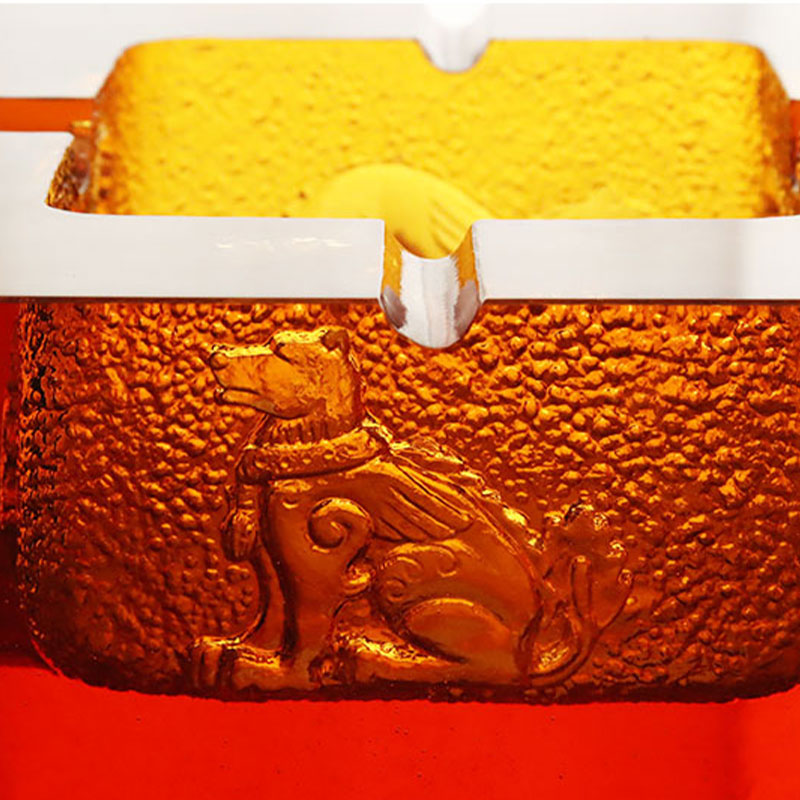 Rødt glassaskebeger med utsøkte pregede dyremønstre