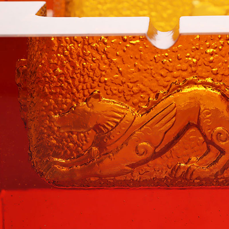 Rødt glassaskebeger med utsøkte pregede dyremønstre