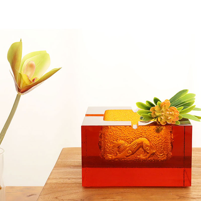 Rødt glassaskebeger med utsøkte pregede dyremønstre